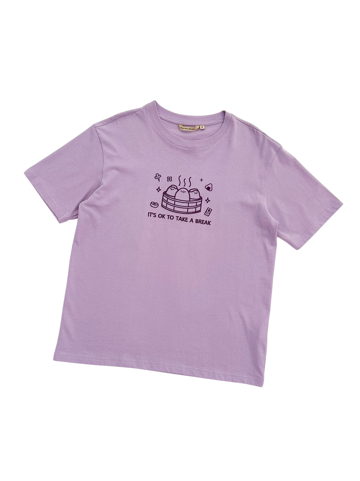 A light purple short-sleeve t-shirt with a dark purple graphic  and the text 'IT'S OK TO TAKE A BREAK' on the front, displayed flat against a white background.